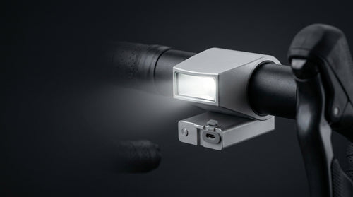 Low-Mount Crash-Safe Headlight clamped low on a black handlebar with its beam lit.
