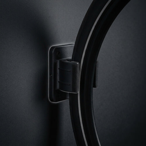 Wall Wheel Clamp in matte black holding a bike tire against a dark wall, seen from the side