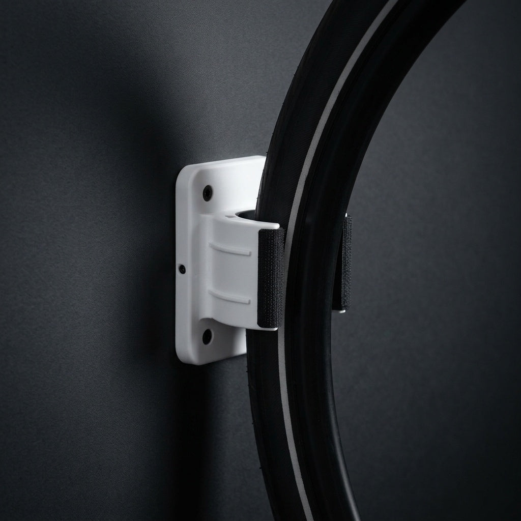 Wall Wheel Clamp in white holding a bike tire against a dark wall, seen from the side