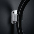 Wall Wheel Clamp in white holding a bike tire against a dark wall, seen from the side