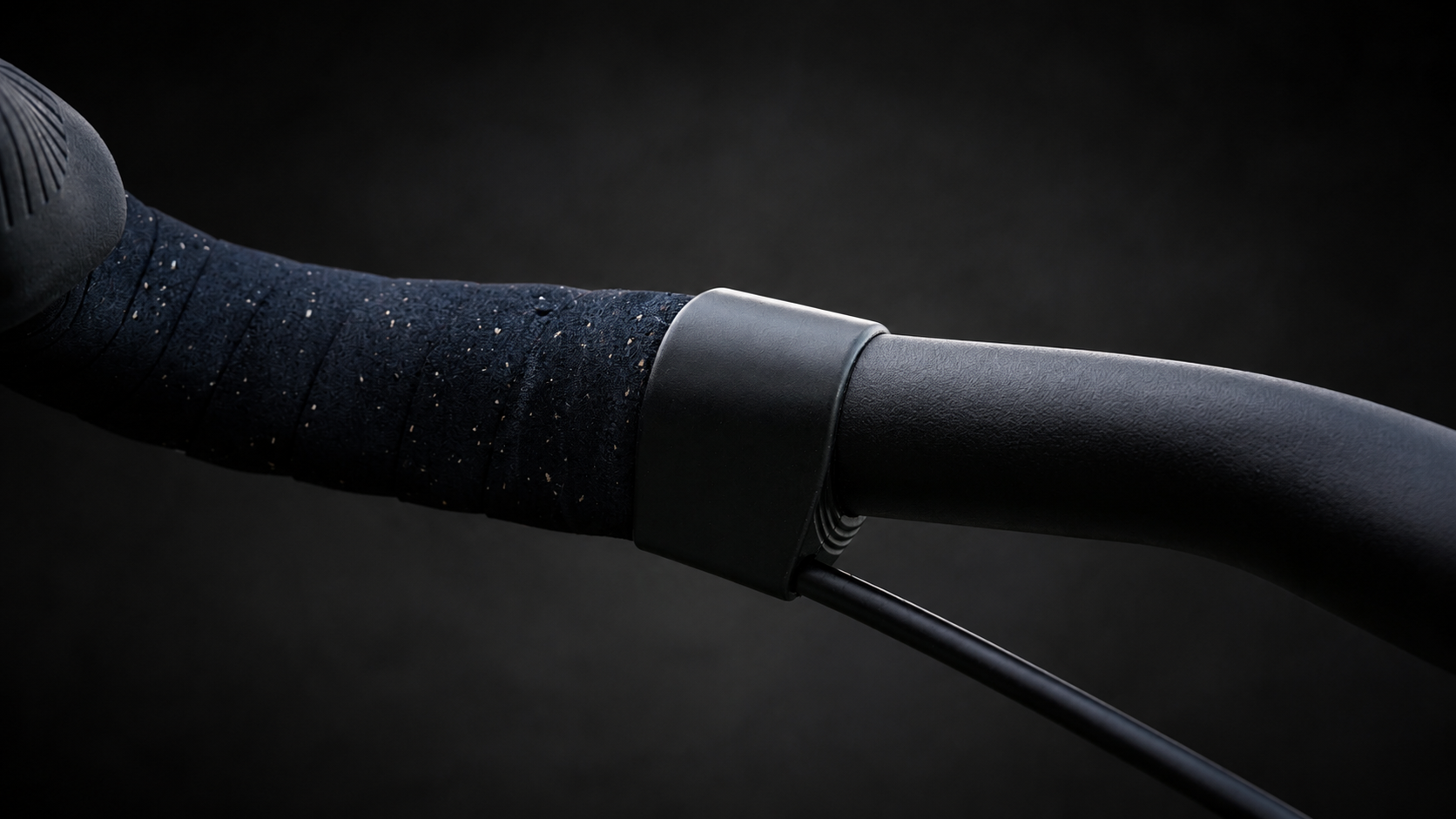 Wrap Clamp in black matte closing the bar tape on a drop bar, angled view